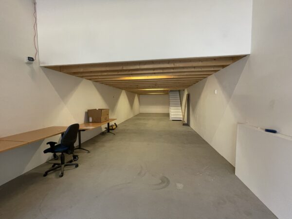 Lege werkruimte aan de Aalsmeerderweg met bureaus, bureaustoel en een houten bovenverdieping met trap.