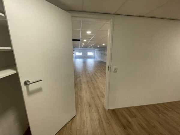 Open deur met zicht op een ruime, lichte kamer met houten vloer aan de Aalsmeerderweg.