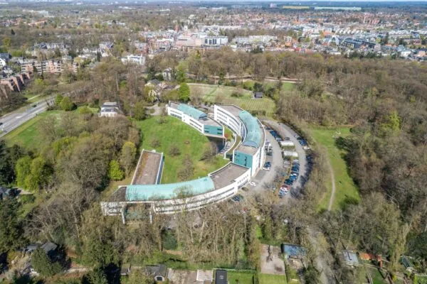 Luchtfoto van het gebouw Sparrenheuvel in een bosrijke omgeving nabij een woonwijk in Zeist.
