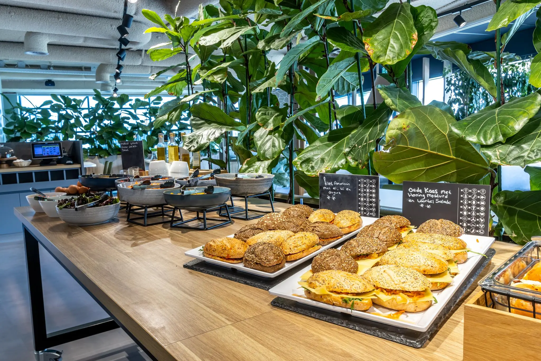 Buffet met diverse belegde broodjes en salades in een groene, moderne ruimte bij Sparrenheuvel.