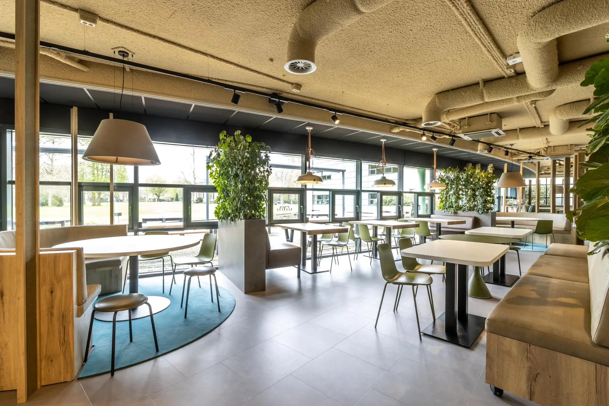 Moderne, licht ingerichte kantine van Sparrenheuvel met groene accenten en een natuurlijke uitstraling.