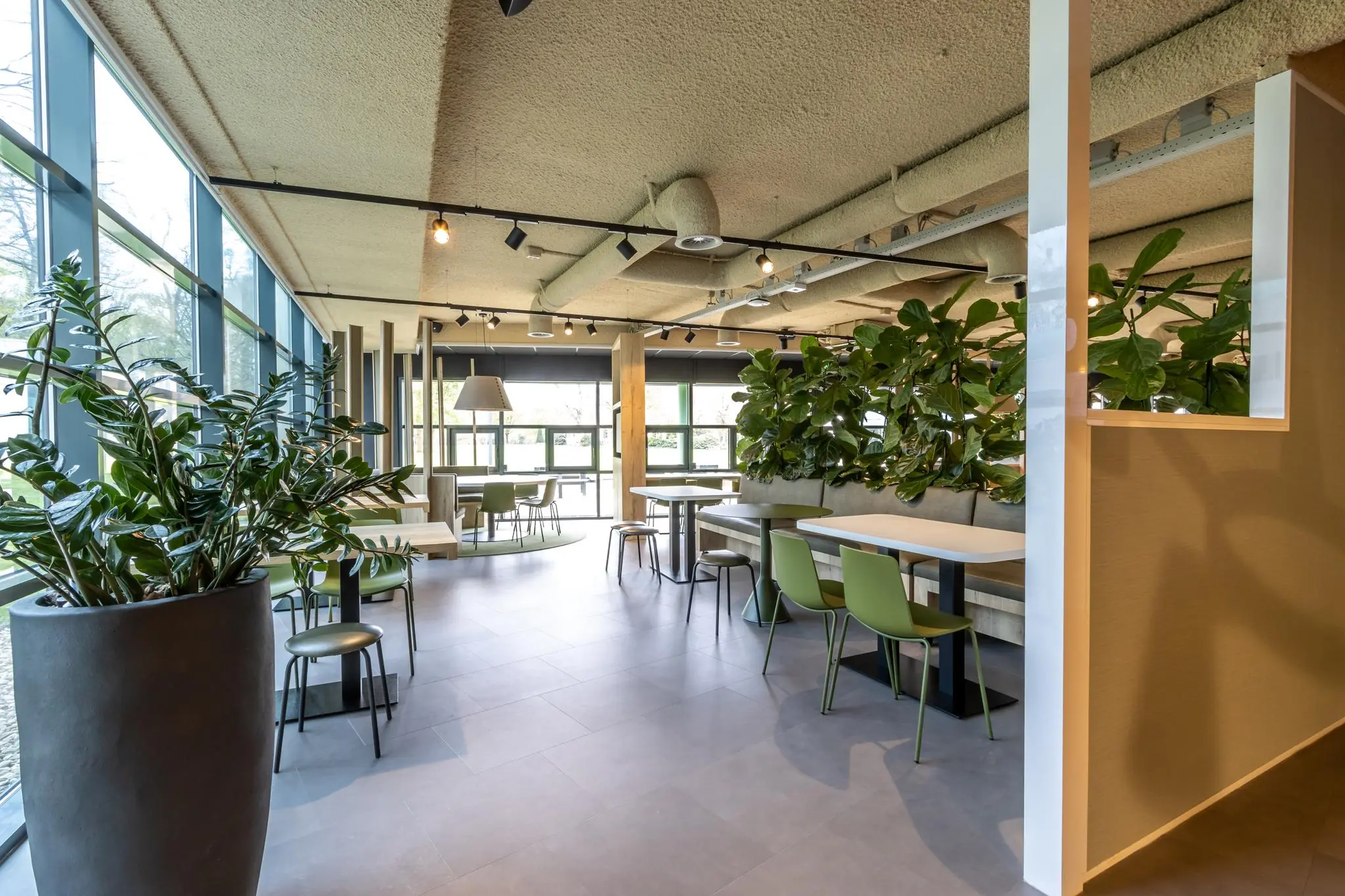 Moderne en licht ingerichte zithoek in kantoorgebouw Sparrenheuvel met veel groen en grote ramen.