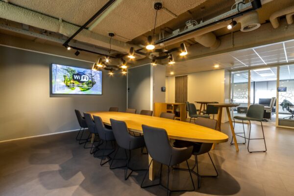 Vergaderruimte Sparrenheuvel met een lange houten tafel, moderne stoelen en een scherm aan de muur.
