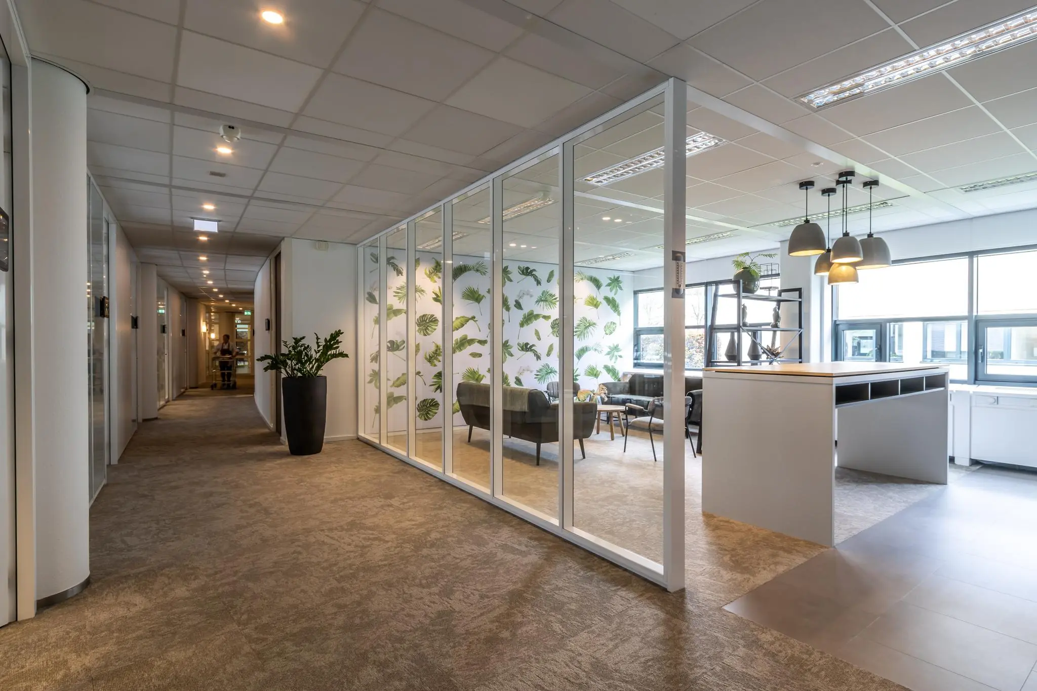 Modern kantoorinterieur in Sparrenheuvel met glazen vergaderruimte, plantenmotief op de muur en open zithoek.