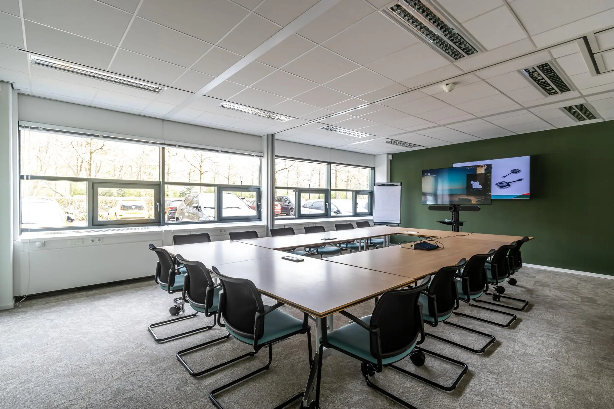 Vergaderruimte Sparrenheuvel met U-vormige opstelling, grote ramen, presentatieschermen en flip-over.