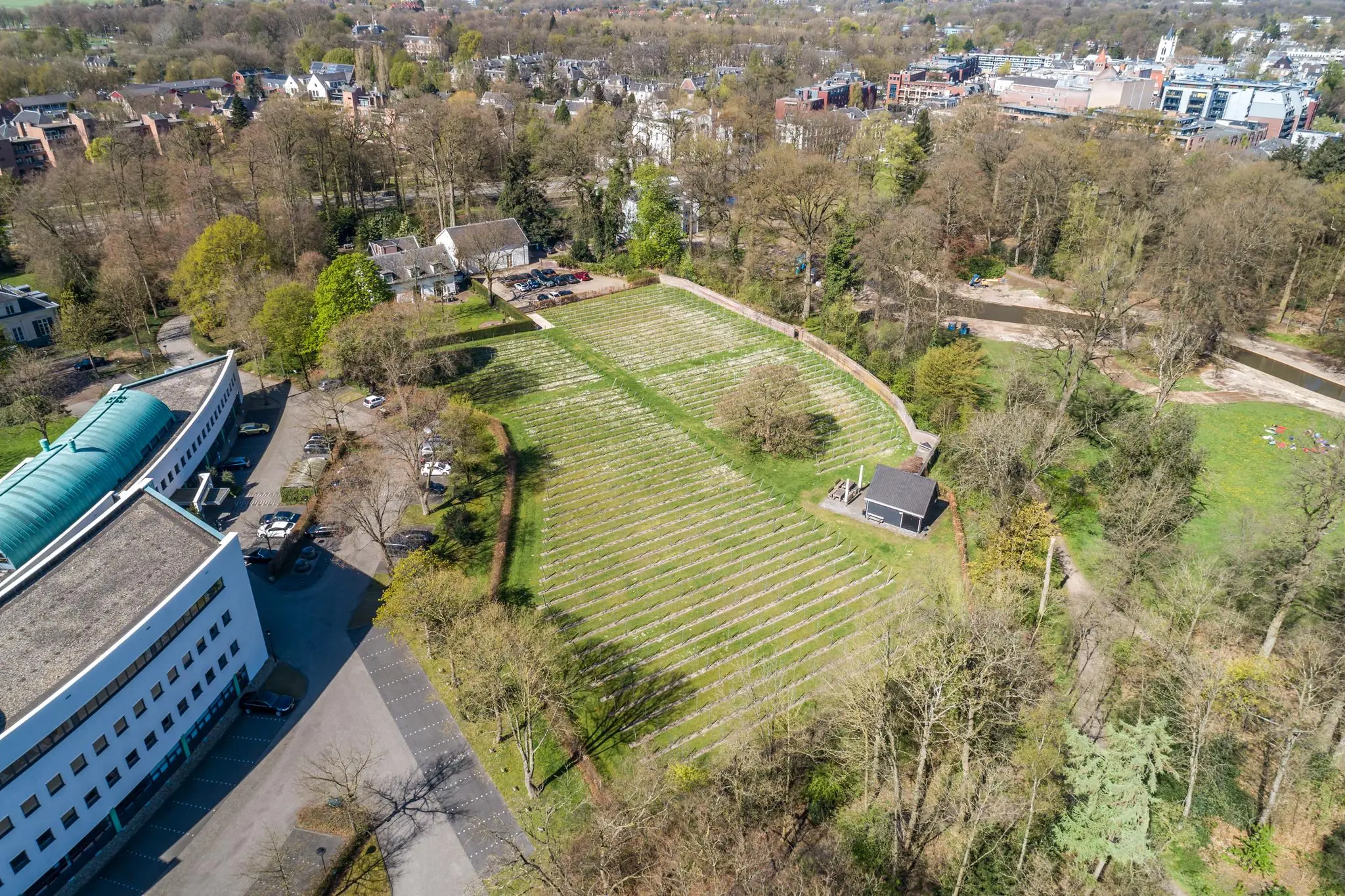 Luchtfoto van begraafplaats Sparrenheuvel in Zeist, omringd door bos en gebouwen.