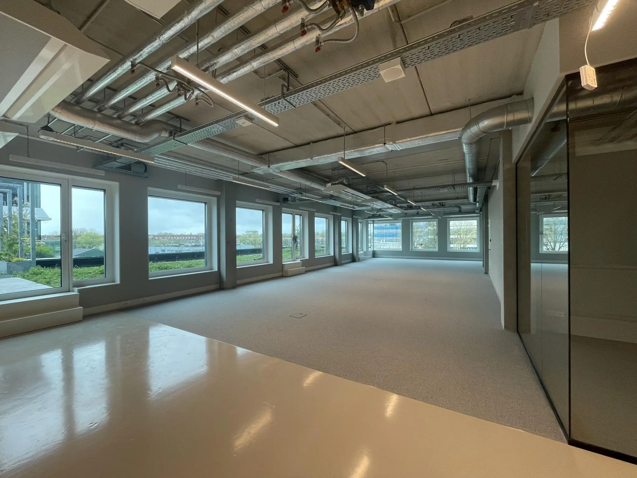 Licht en modern kantoorpand aan de Asterweg met grote ramen en een industrieel plafond.