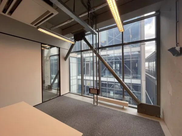 Kantoorruimte met grote ramen en uitzicht op het moderne kantoorgebouw aan de Danzigerkade.