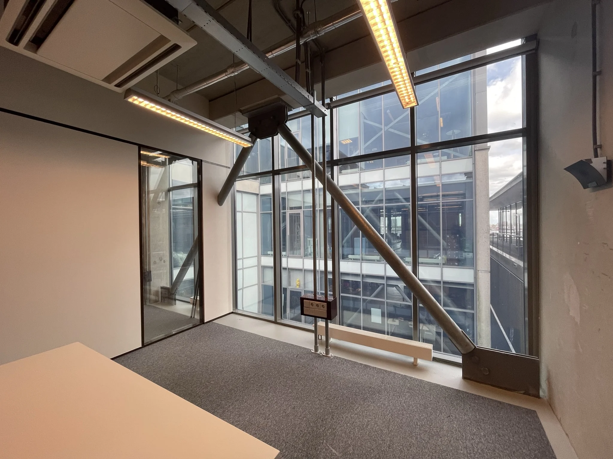 Kantoorruimte met grote ramen en uitzicht op het moderne kantoorgebouw aan de Danzigerkade.