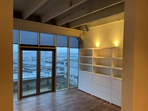 Modern ingerichte kamer met grote ramen en uitzicht op de Danzigerkade in Amsterdam.