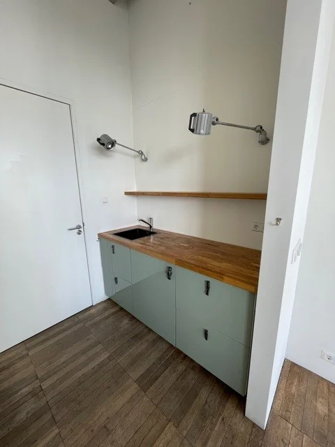 Kleine kitchenette aan de Danzigerkade met houten werkblad, mintgroene kastjes en twee wandlampen.