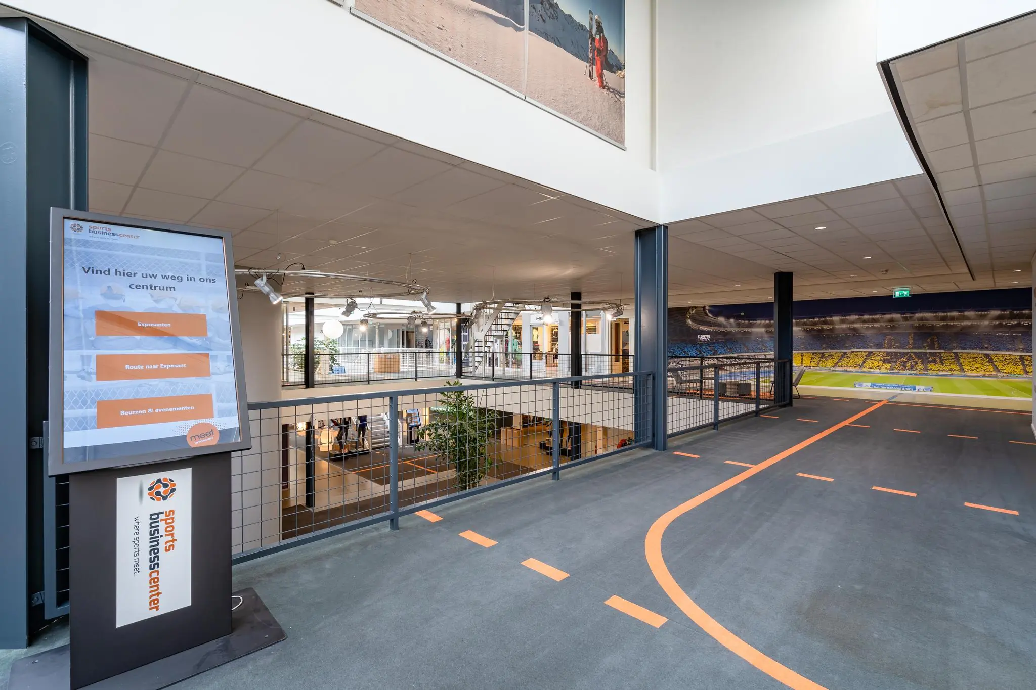 Binnenruimte van het Sports Business Center aan de Plesmanstraat met informatiezuil en sportvelddecoratie op de muur.