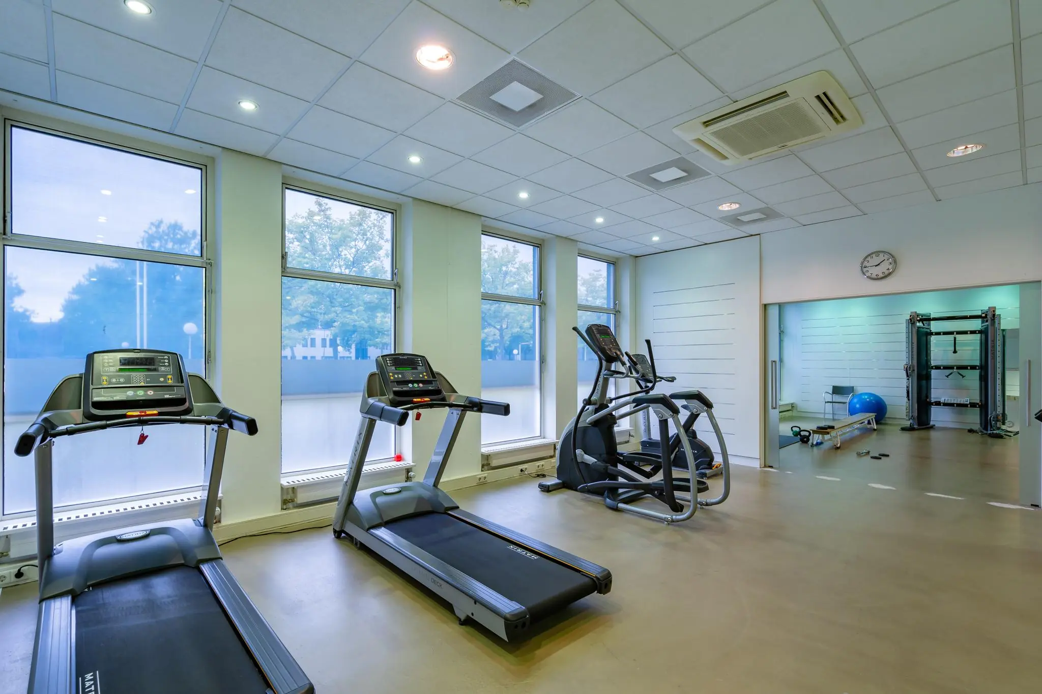 Moderne fitnessruimte aan de Plesmanstraat met loopbanden, een crosstrainer en diverse trainingsapparaten.