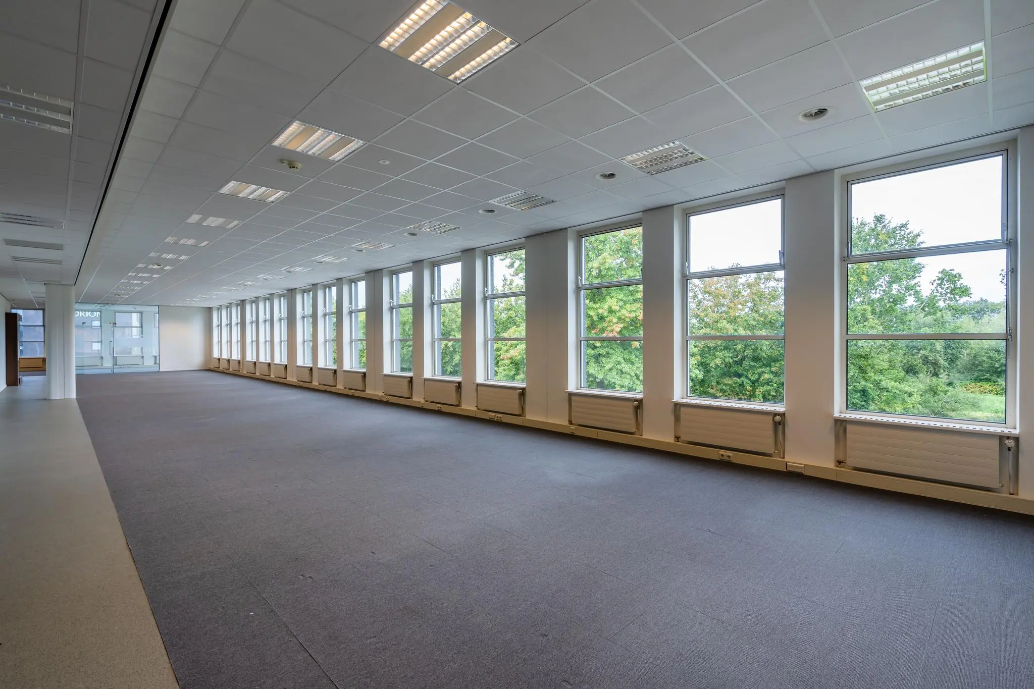 Lichte, lege kantoorruimte aan de Plesmanstraat met grote ramen en uitzicht op groen.