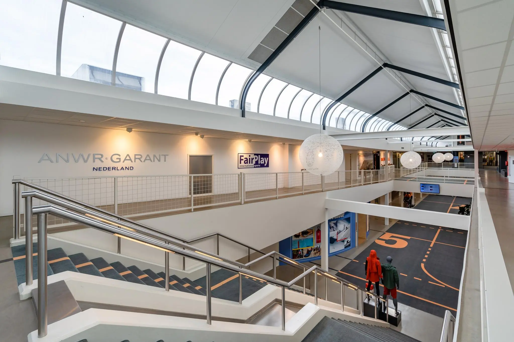 Modern winkel- en kantoorpand aan de Plesmanstraat met open trap, glazen dak en zicht op ANWR-GARANT en FairPlay Sports.