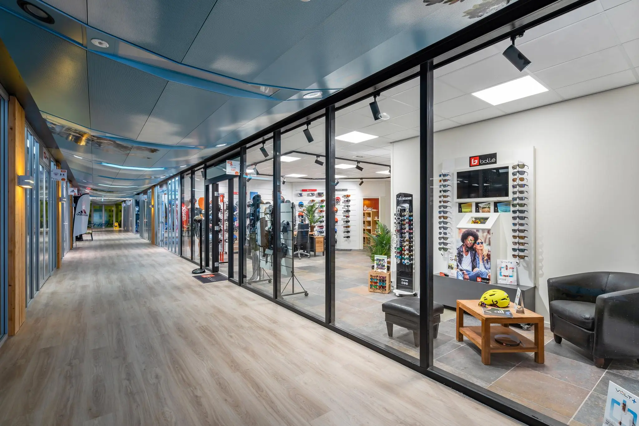 Moderne winkelgalerij aan de Plesmanstraat met een sport- en brillenwinkel achter glazen wanden.