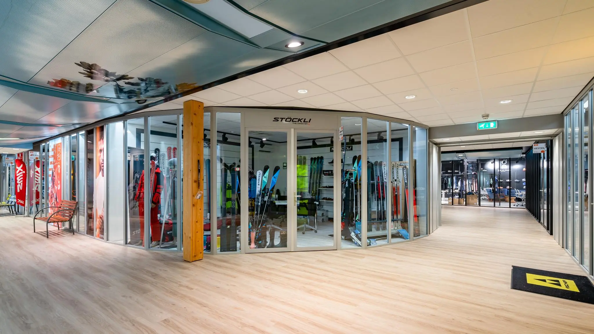 Moderne gang in een wintersportwinkel aan de Plesmanstraat met glazen vitrines vol ski-uitrusting van het merk Stöckli.
