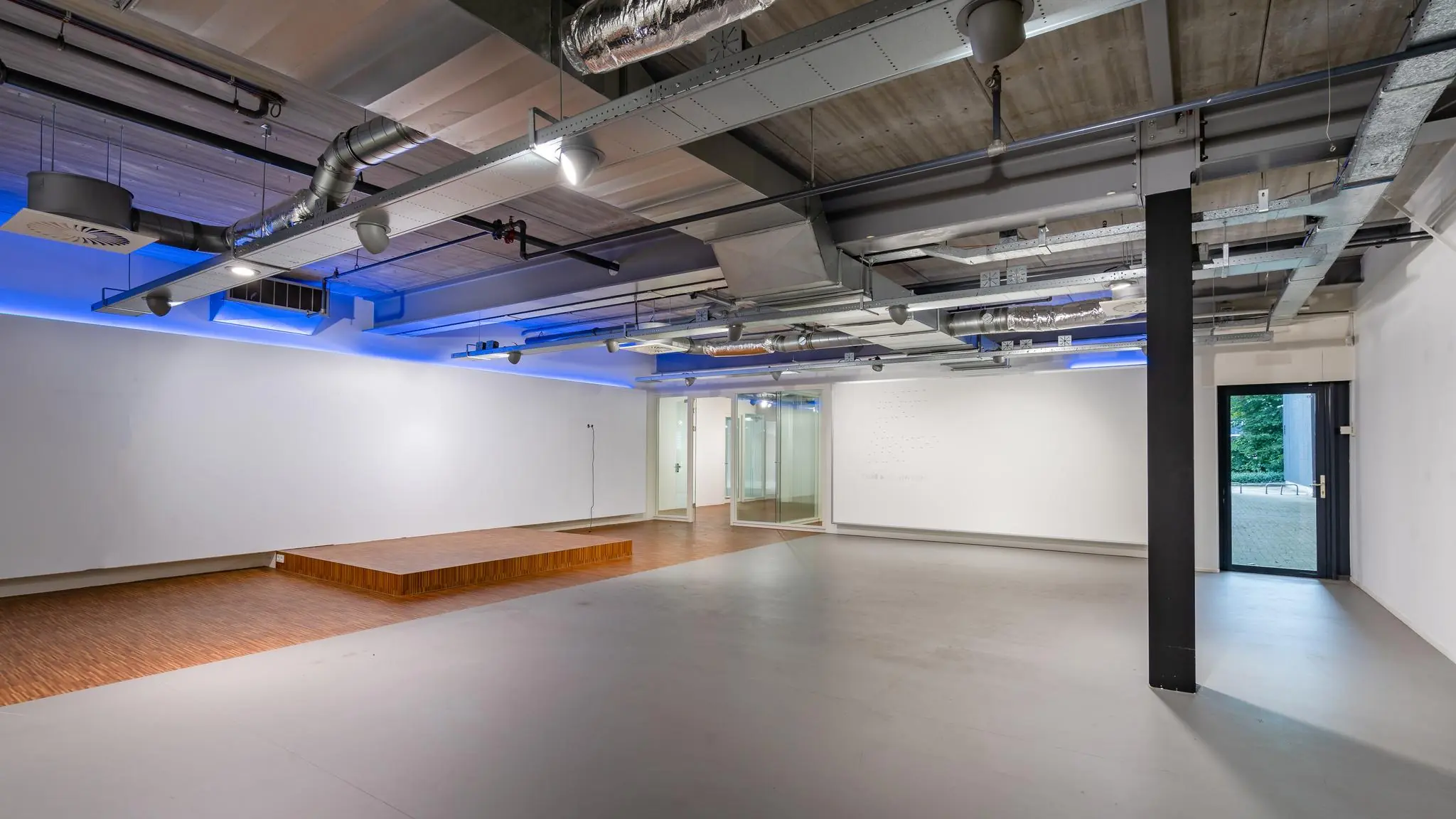 Moderne, lege kantoorruimte aan de Plesmanstraat met industriële plafonddetails en een kleine houten podiumvloer.