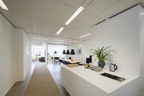Moderne kantoorruimte aan de Helicopterstraat met open keuken, lange vergadertafel en glazen vergaderruimte.