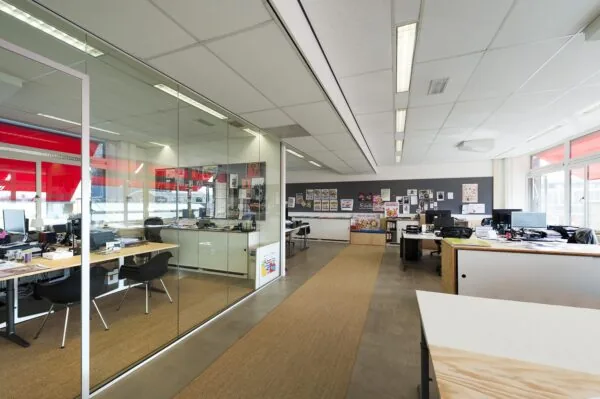 Modern kantoorinterieur aan de Helicopterstraat met glazen vergaderruimte en werkplekken langs grote ramen.