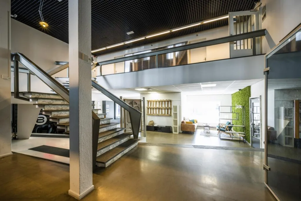 Moderne kantoorruimte aan de Vliegtuigstraat met een open trap, glazen wanden en een loungegedeelte met groene moswand.