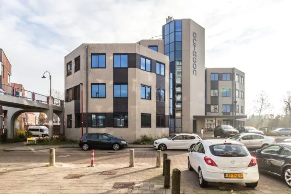 Modern kantoorgebouw aan de Dukatenburg met geparkeerde auto's op de voorgrond.