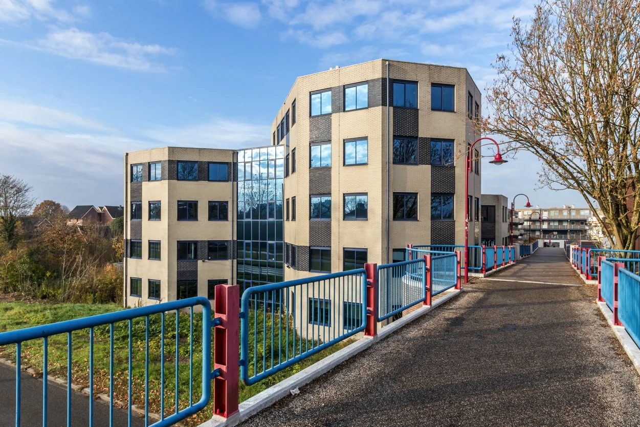 Modern kantoorgebouw aan de Dukatenburg in Nieuwegein gezien vanaf een voetgangersbrug met blauwe en rode leuningen.