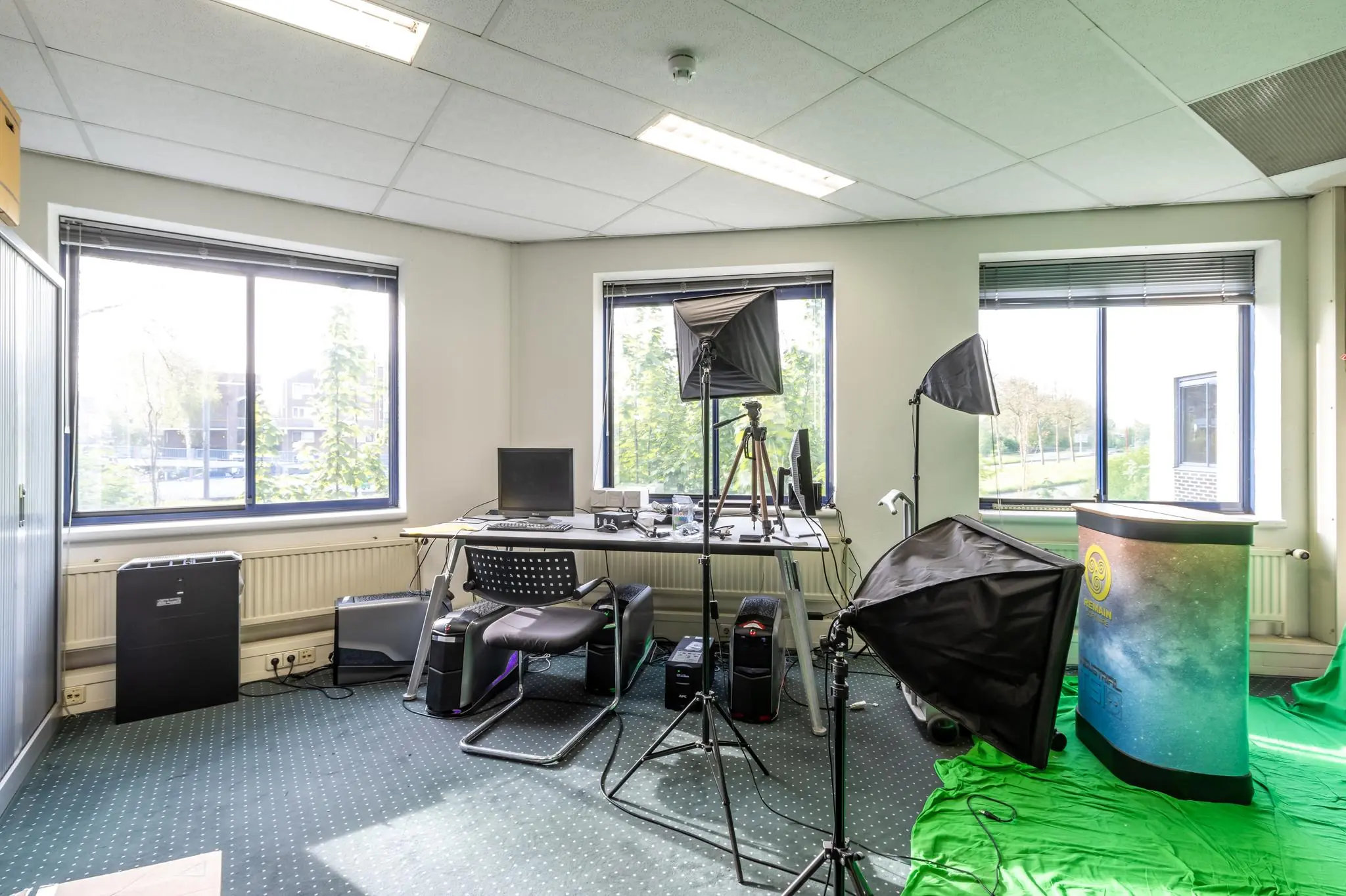 Opname van een kantoorruimte aan de Dukatenburg met computerapparatuur, studiobelichting en een groene achtergrond voor videoproductie.
