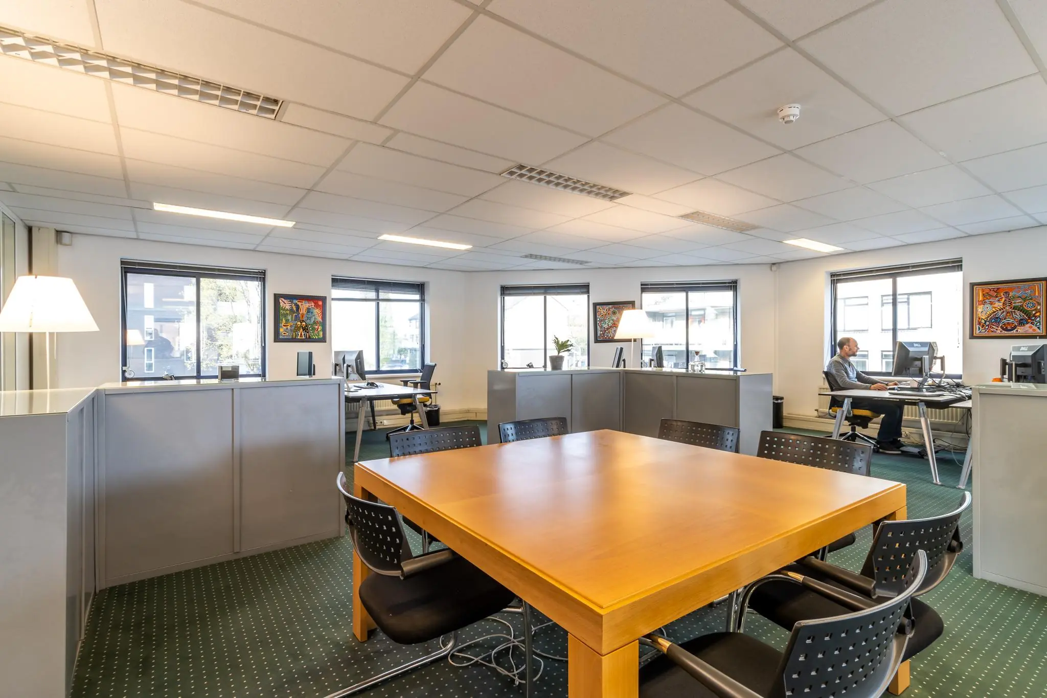Modern kantoorinterieur met bureaus, vergadertafel en een medewerker aan het werk bij Dukatenburg.