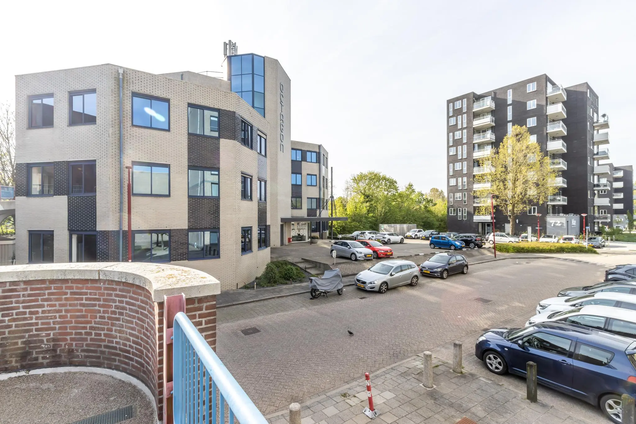 Voorzijde van het kantoorgebouw Dukatenburg met parkeerterrein en omliggende appartementen.