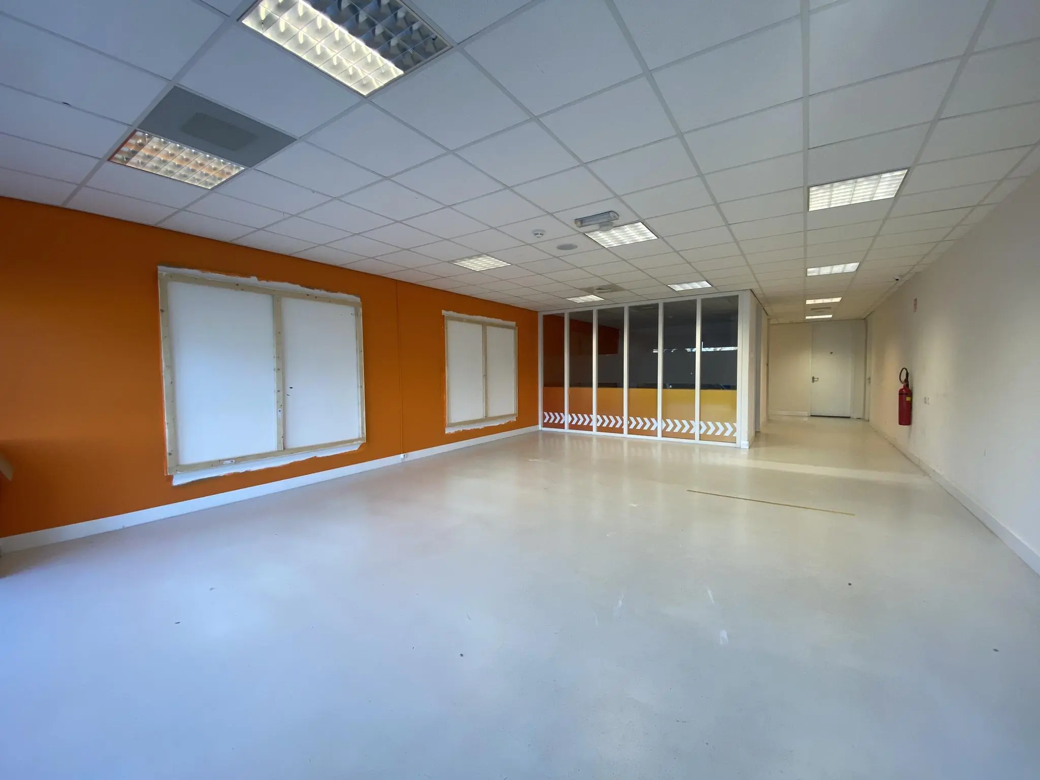 Leegstaande kantoorruimte aan het Herculesplein met oranje muur en glazen scheidingswand.