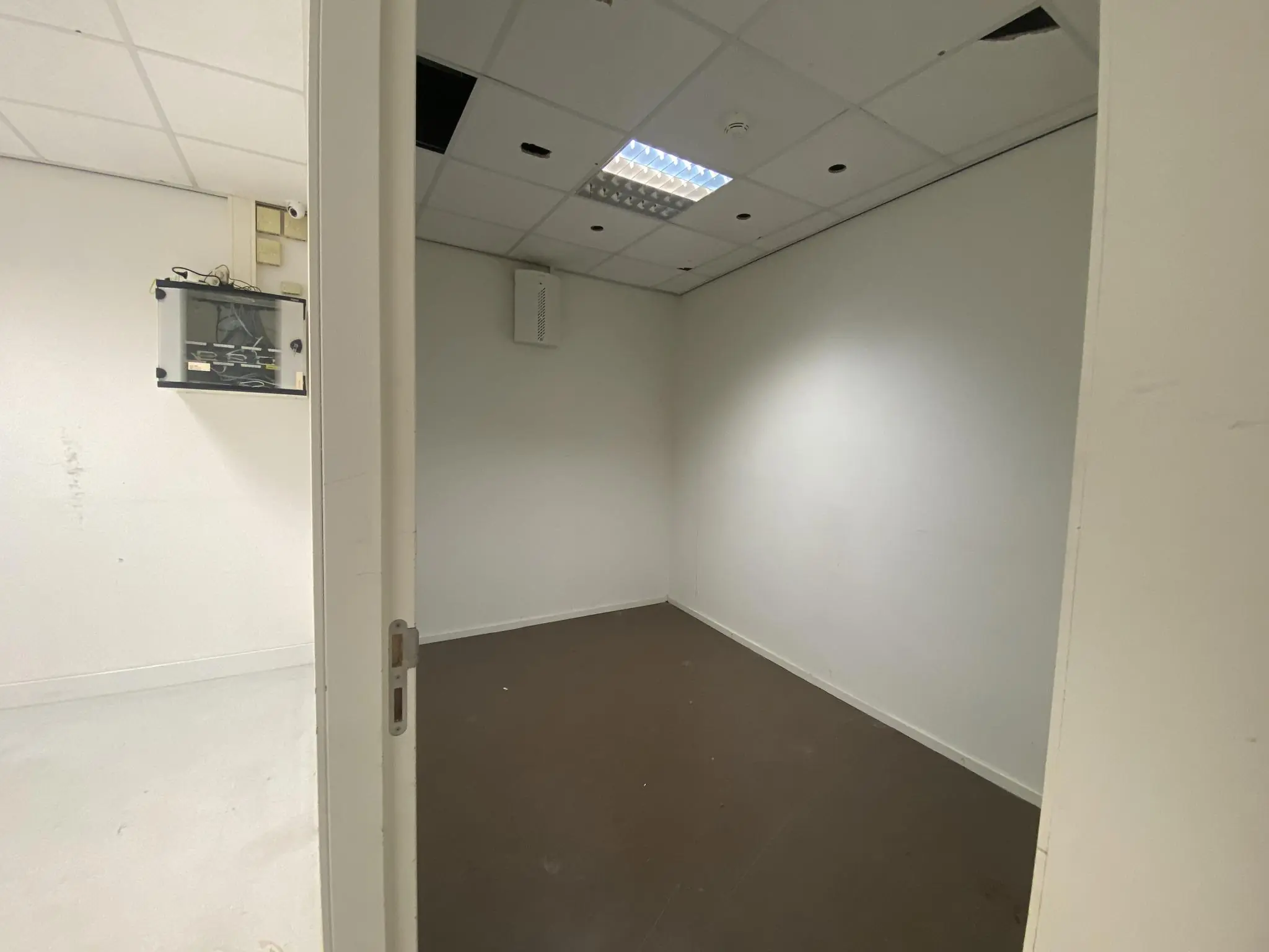 Lege, kleine kantoorruimte op Herculesplein met systeemplafond en deels open plafondplaten.