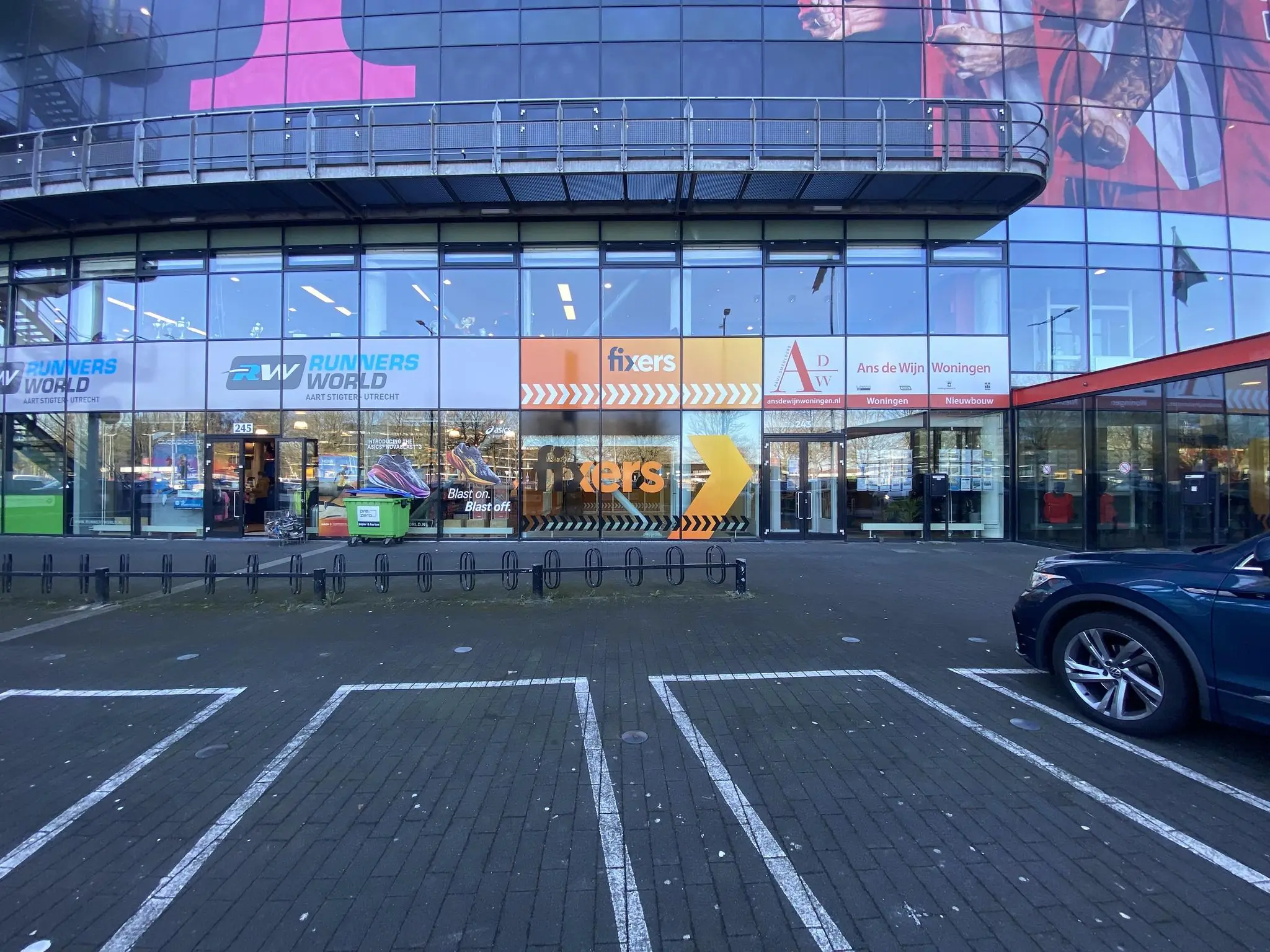 Voorgevel van een winkelpand aan het Herculesplein met onder andere Runnersworld, Fixers en Ans de Wijn Woningmakelaars.