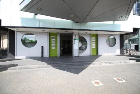 Ingang van een modern kantoorgebouw aan het Herculesplein met ronde ramen en groene accenten.