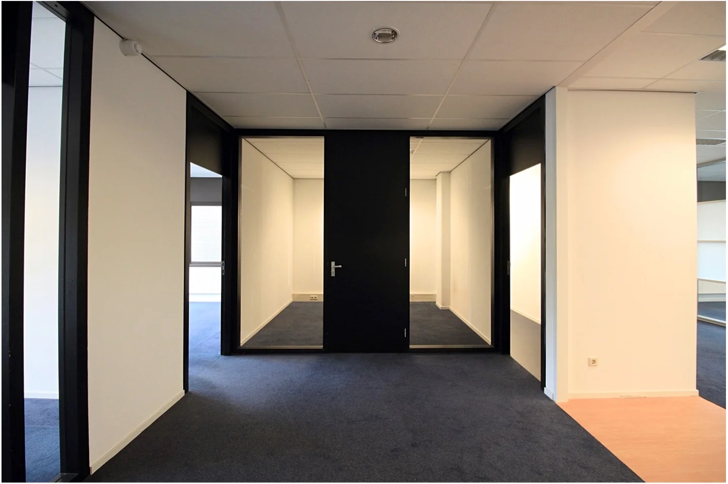 Moderne kantoorruimte aan het Herculesplein met zwart-witte wanden en blauwe vloerbedekking.