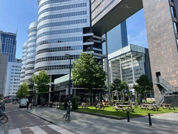 Moderne kantoorgebouwen en een groen plein met picknicktafels aan het Weena in Rotterdam.