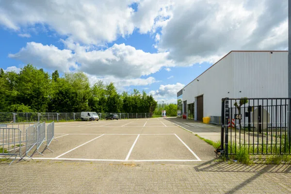 Leeg parkeerterrein naast een wit industrieel gebouw aan de Calandstraat, met enkele geparkeerde voertuigen en groene bomen op de achtergrond.