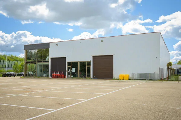 Wit bedrijfsgebouw aan de Calandstraat met grote roldeuren en lege parkeerplaatsen op de voorgrond.