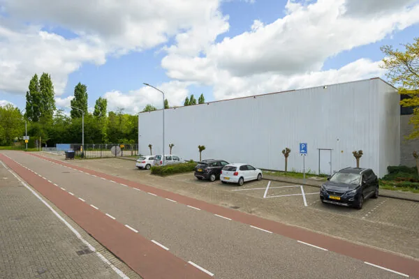 Parkeervakken met enkele auto's langs een wit industrieel gebouw aan de Calandstraat.