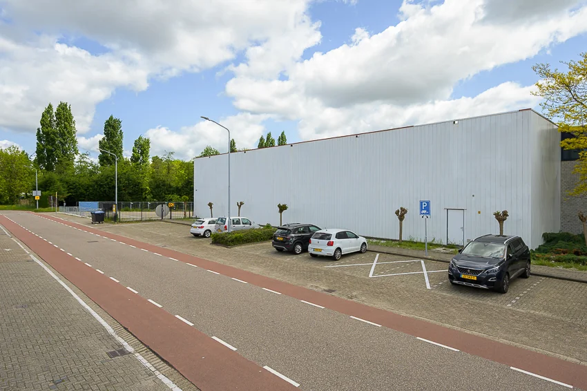 Parkeervakken met enkele auto's langs een wit industrieel gebouw aan de Calandstraat.