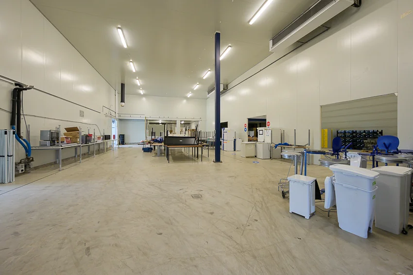 Ruime, goed verlichte industriële werkruimte aan de Calandstraat met werkbanken, apparatuur en afvalbakken.