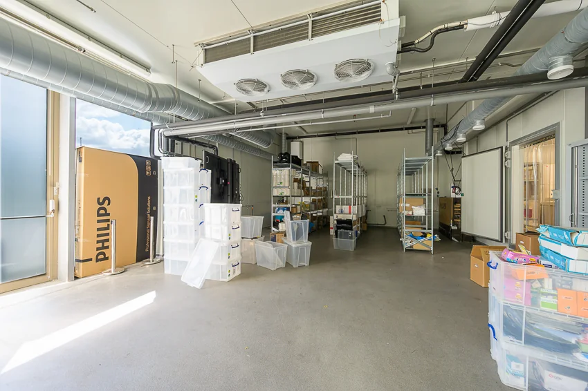 Opslagruimte aan de Calandstraat met rekken, plastic boxen en een grote Philips-doos bij de ingang.