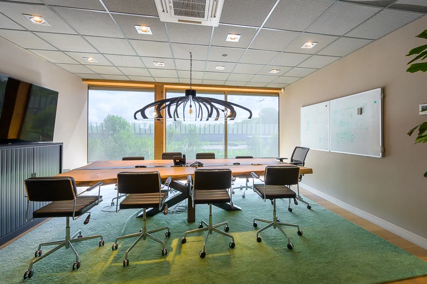 Moderne vergaderruimte aan de Calandstraat met een grote houten tafel, designstoelen, groot raam en een opvallende hanglamp.