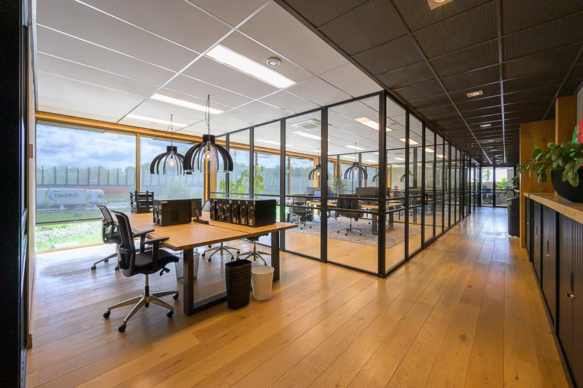 Modern kantoorinterieur aan de Calandstraat met glazen wanden, houten vloer en werkplekken met bureaustoelen.