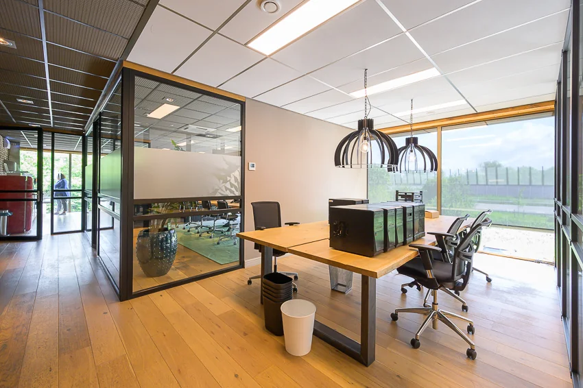 Moderne kantoorruimte aan de Calandstraat met glazen vergaderruimte, houten vloer en grote ramen met veel daglicht.