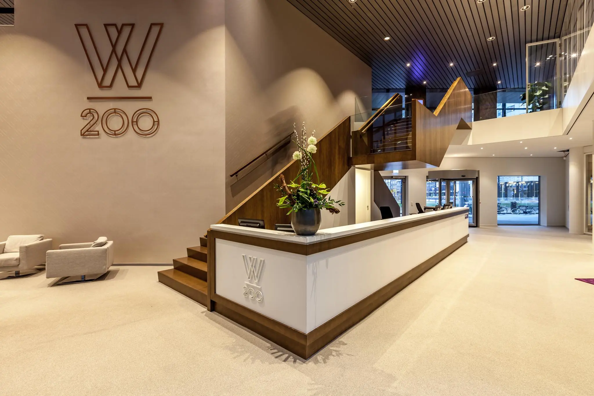 Moderne ontvangsthal van het kantoorgebouw Weena 200 met een receptiebalie, trap en stijlvolle inrichting.