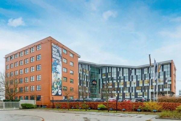 Kantoorgebouw aan de Siriusdreef met een gevelbanner waarop staat "WE GIVE WORK".