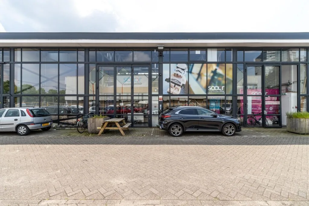 Bedrijfsgebouw aan de Eendrachtlaan met glazen gevel, geparkeerde auto's en een groot Socar-reclamebord.