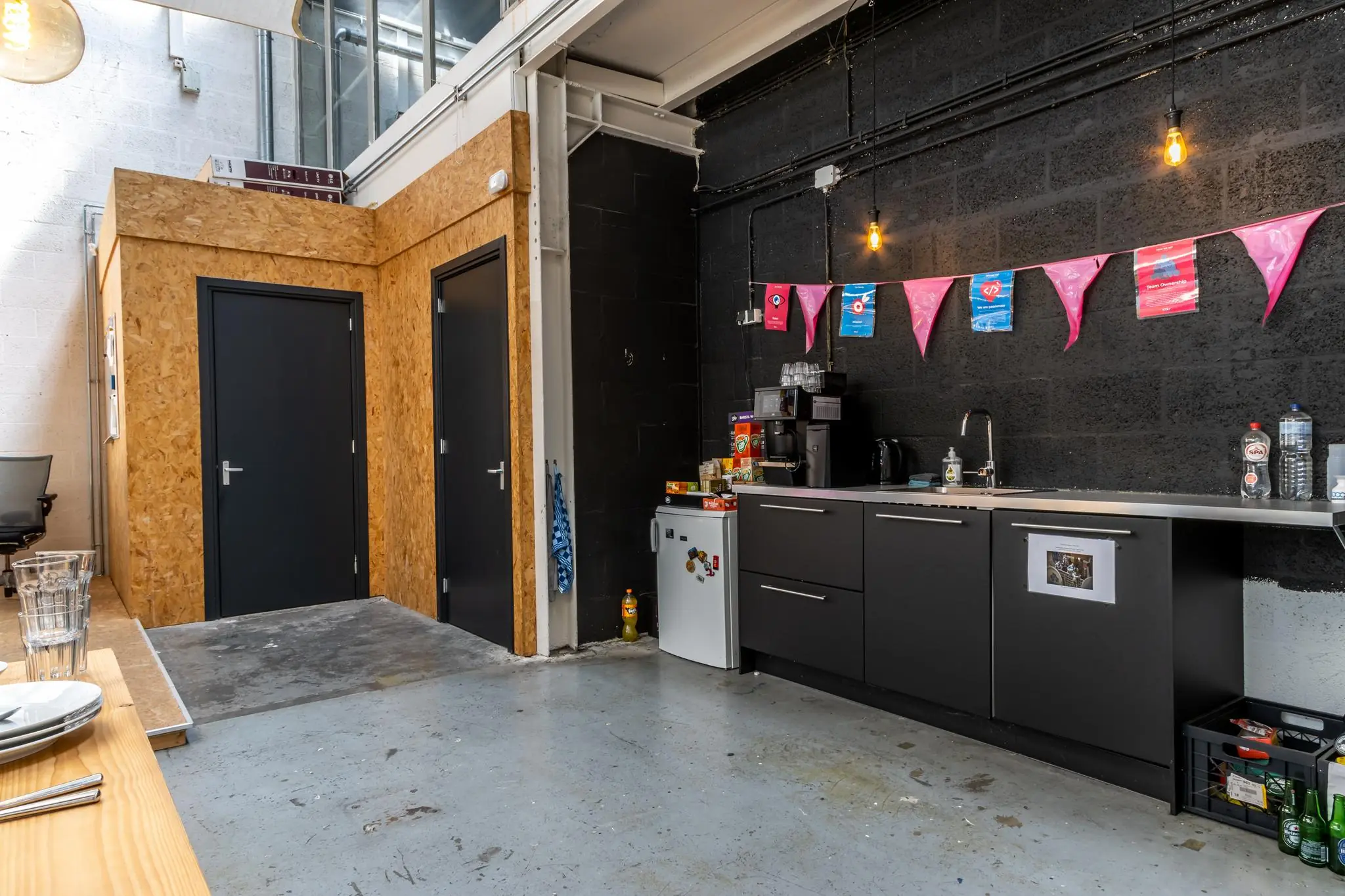 Keukenblok in een industriële kantoorruimte aan de Eendrachtlaan, met koffiezetapparaat, koelkast en feestelijke slingers.