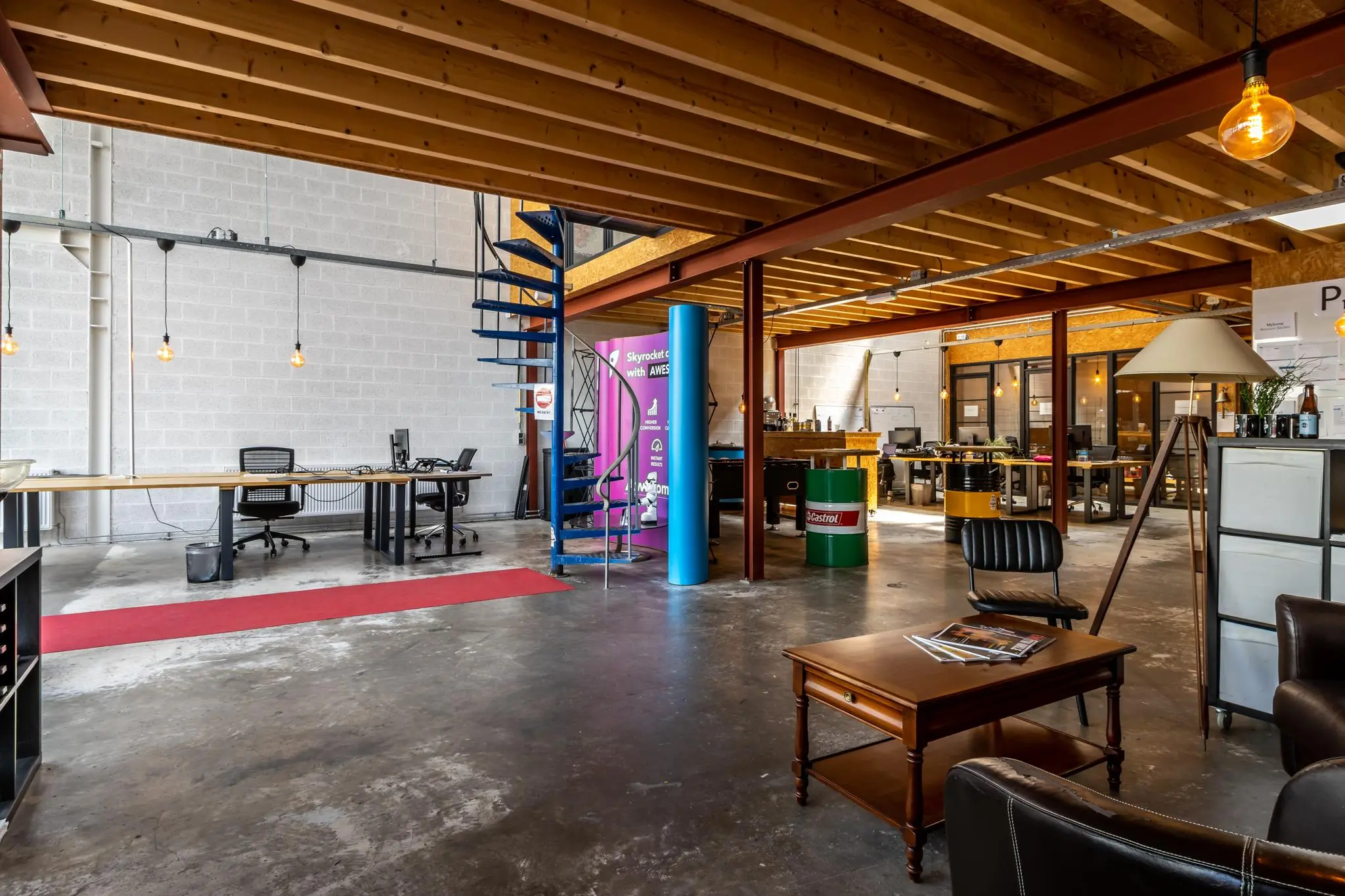 Modern ingericht bedrijfs- of kantoorinterieur aan de Eendrachtlaan met open werkplekken, zichtbare houten balken en een metalen wenteltrap.